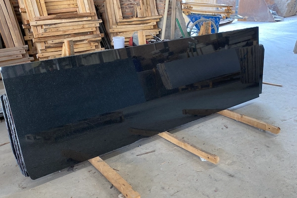 Polished Absolute Black Granite slabs on timber supports in a supplied factory gloss-review image