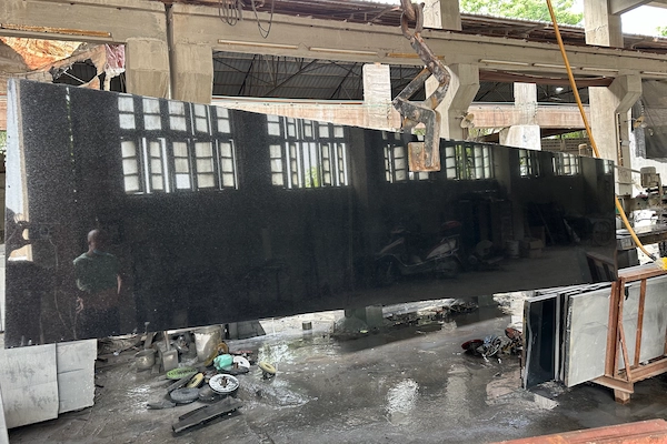 Polished Absolute Black Granite slab on a factory rack during a supplied quality-acceptance review