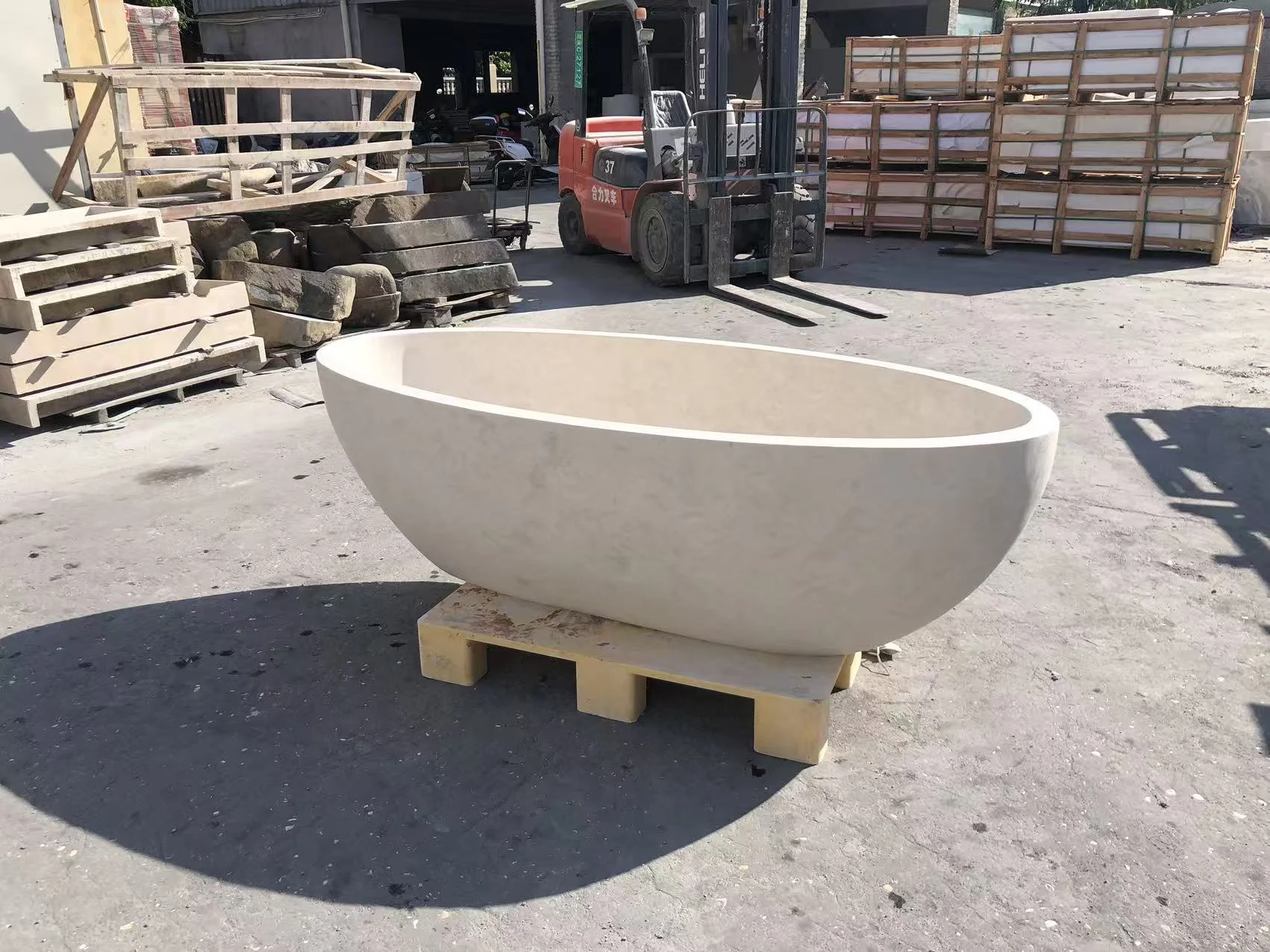 Beige limestone freestanding bathtub on a support base in a factory yard