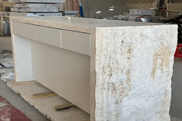 Beige limestone reception desk with a textured stone front and internal carcase shown during workshop review