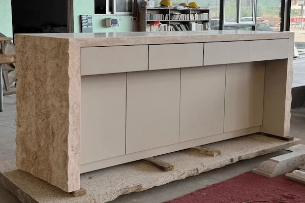 Staff-side view of a beige limestone reception desk showing the internal carcase and cabinet faces during workshop review