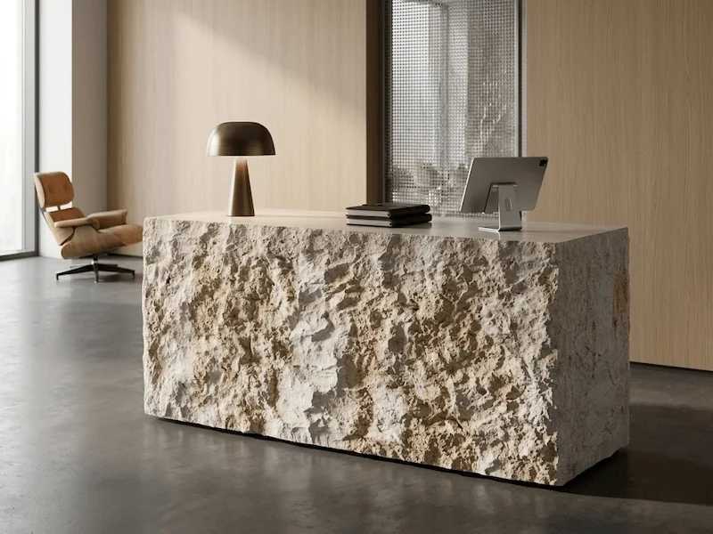 Beige limestone reception desk with a textured split-face front and smooth counter surface in a styled interior