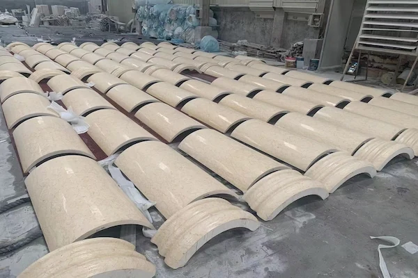 Curved Beige Marble column shaft components arranged in a stone workshop