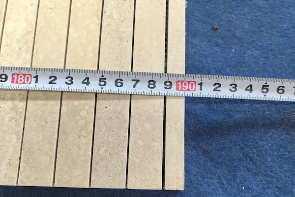 Beige Travertine Linear Mosaic pieces shown in a supplied thickness tolerance check reference image