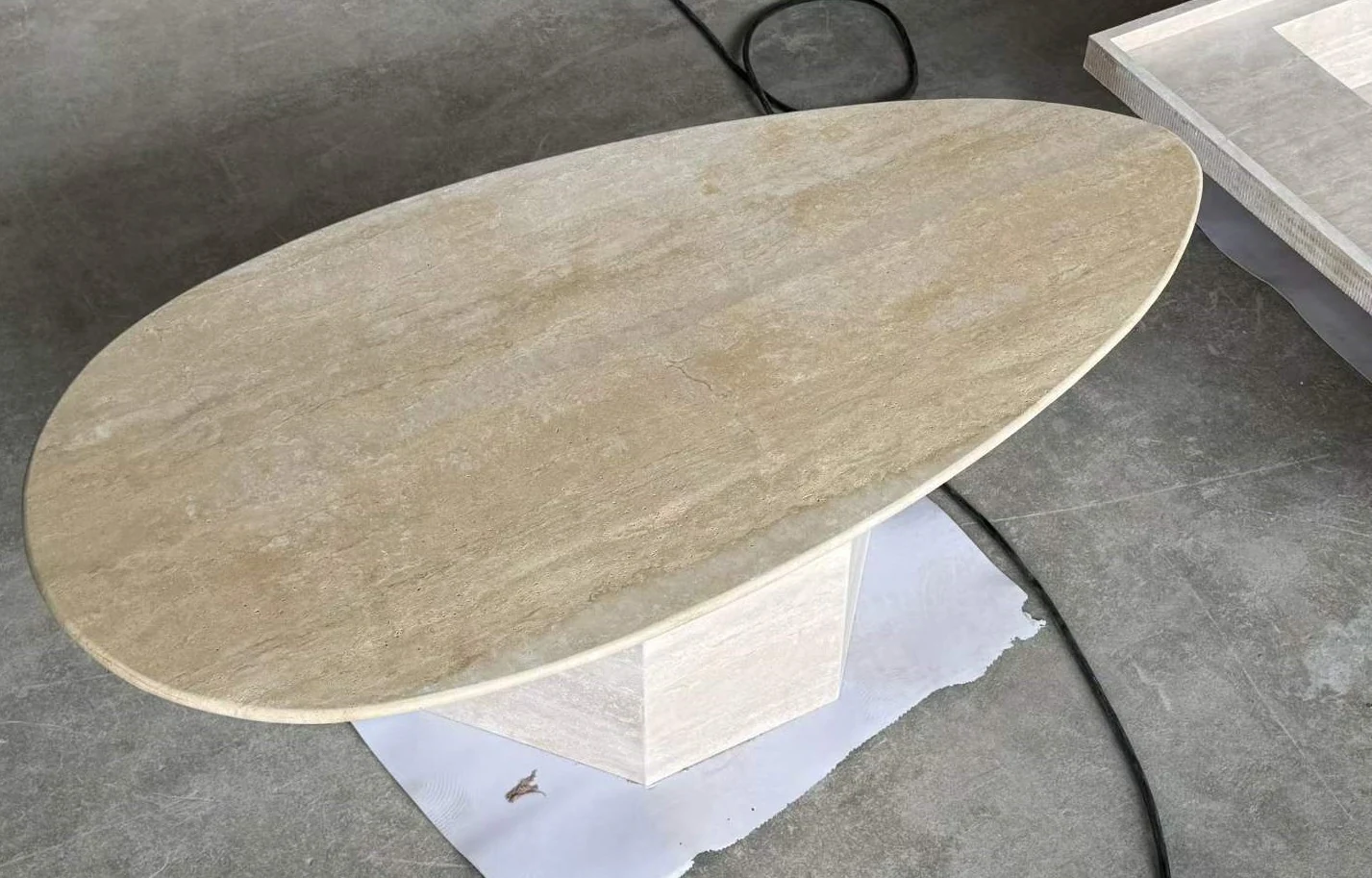 Oval beige travertine coffee table top shown during workshop surface review