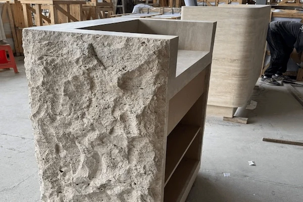 Beige travertine reception desk with a deeply textured split-face front shown during workshop review