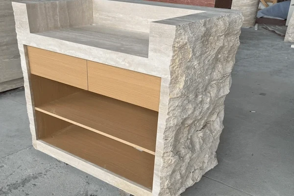 Staff-side view of a split-face travertine reception desk showing open internal storage during workshop review