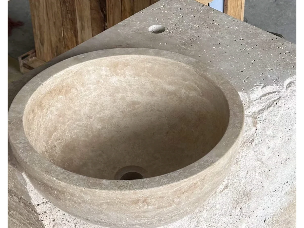 Natural split-face travertine front edge checked during wall-mounted vanity production