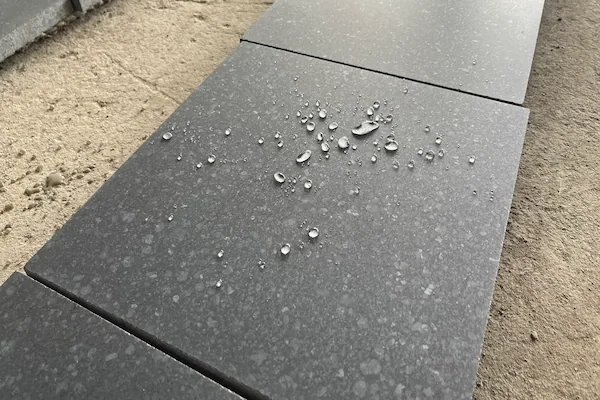 Honed G684 Black Basalt tiles with water droplets in a supplied surface-observation image