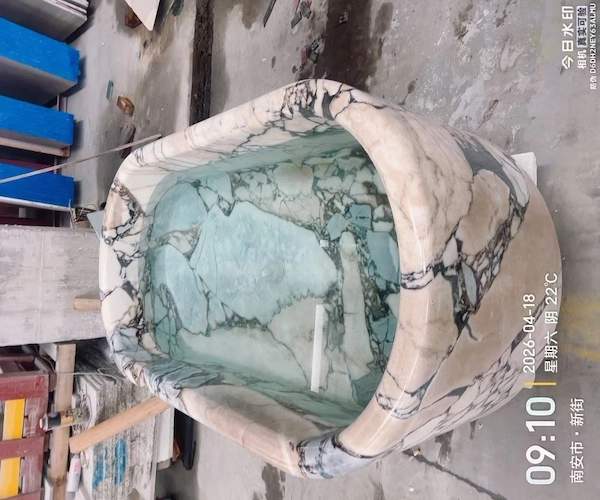 Supplied workshop reference of a Calacatta Viola marble bathtub filled with water and viewed from above