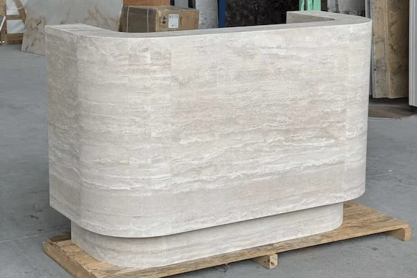 Beige travertine curved reception desk showing horizontal stone movement during workshop review