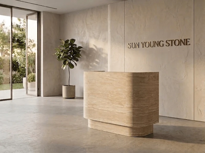 Curved beige travertine reception desk with horizontal stone movement and an integrated carcase in a styled interior