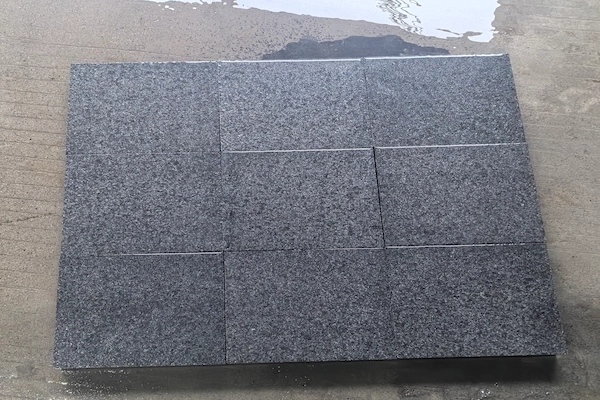 Cut G654 Granite paving units arranged in a rectangular panel on a wet work surface
