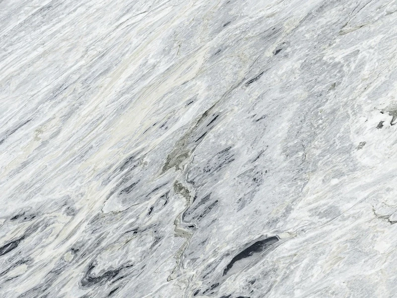 Manhattan Marble slab surface in cool white-grey tones with elongated graphite and soft black movement