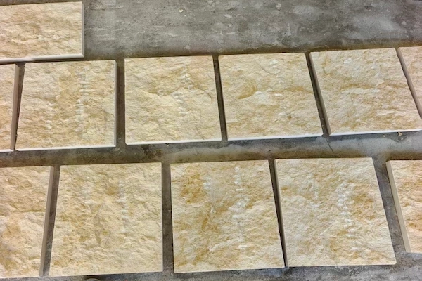 Supplied reference of beige Rock Face Limestone cladding pieces arranged on a work surface for visual review