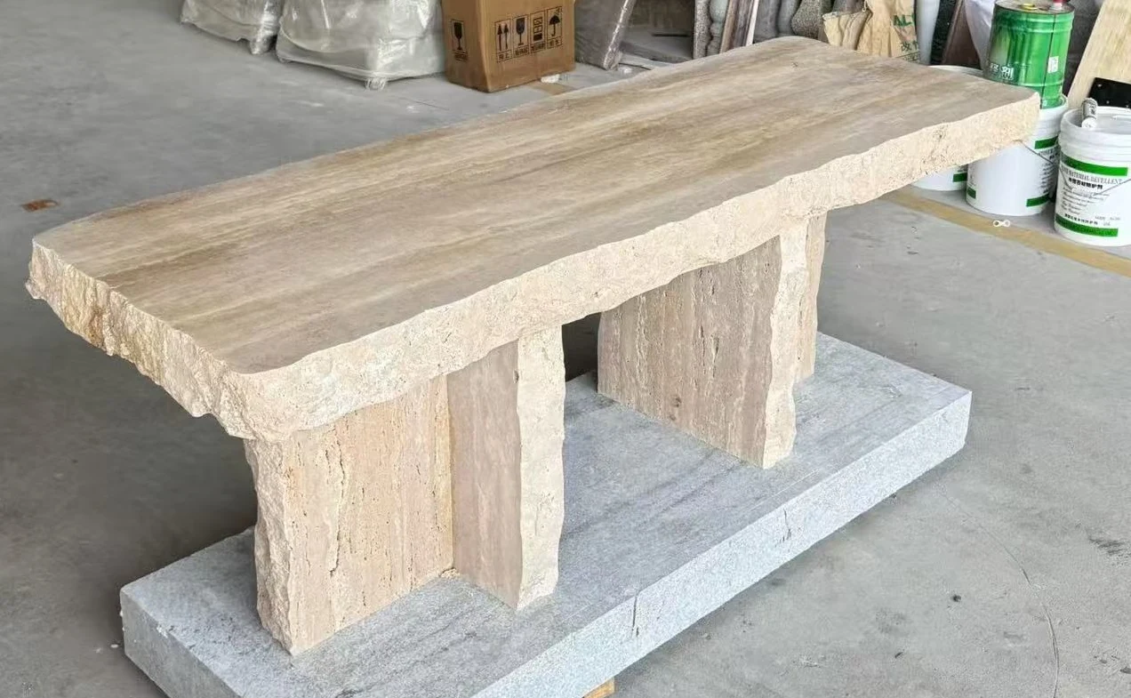 Rectangular travertine coffee table with textured block supports shown in a stone furniture workshop