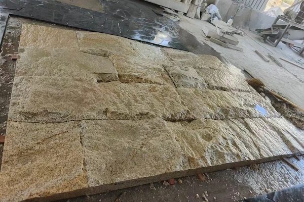 Rusty Yellow Granite split-face panels during thickness review in a supplied factory inspection image