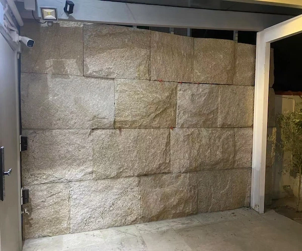 Rusty Yellow Granite natural-split wall cladding shown around an entrance in a supplied wall-construction reference