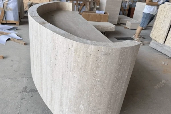 Curved beige travertine reception desk shell shown from above during workshop review