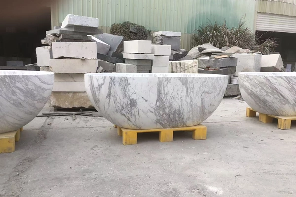Supplied workshop-yard reference showing the veined surface of a Volakas White marble oval bathtub on a support pallet