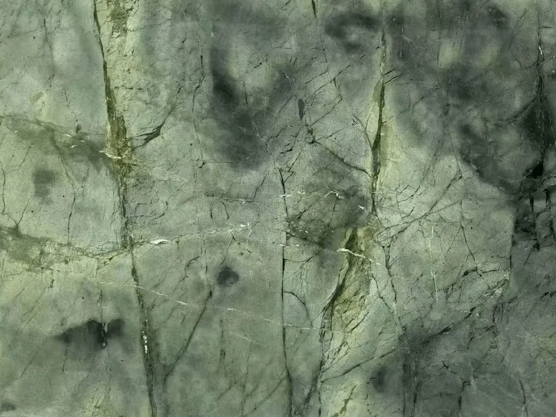Wizard of Oz Quartzite slab surface in olive to grey-green tones with clouded dark inclusions and fine linear movement